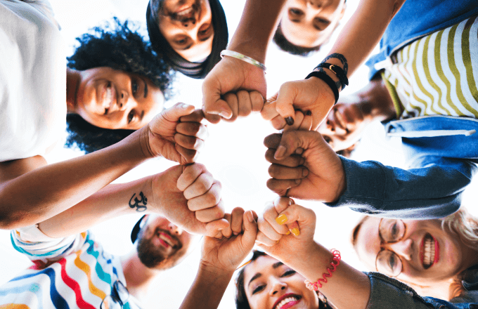 A group of diverse youth gathering fists in a momentum of teamwork and inclusivity